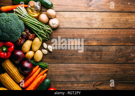 Ensemble d'un assortiment de légumes frais situées près de bouteille d'huile sur le côté de la table de bois d'oeuvre Banque D'Images