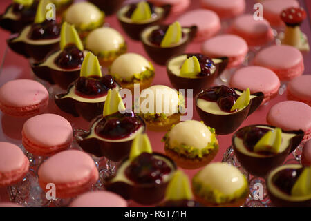 Close-up of disposition symétrique petits gâteaux et macarons sur un affichage en verre élégante, un délicieux dessert variété à une réception de mariage Banque D'Images