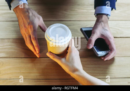 Barista sert du café à un homme. Coupe papier en plastique table en bois Pause Blazer. Pause café Concept Banque D'Images