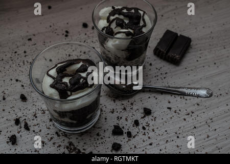Du yaourt fait maison de cookies, chocolat et crème avec des miettes sur la table en bois Banque D'Images