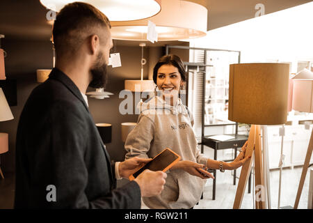 Belle dark-haired dame debout en gris à capuche et de toucher la lampe haute Banque D'Images