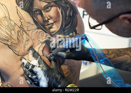 CIRCA 2018 ALICANTE JUSTE TATOUAGE tatoueur concentré le travail avec des gants noir Banque D'Images