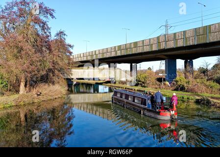 Un petit bateau sur la jonction de la voie navigable Wey et la Basingstoke canal à New Haw, avec l'augmentation de la section de l'autoroute M25,Surrey England Banque D'Images