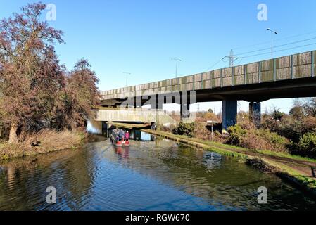 Un petit bateau sur la jonction de la voie navigable Wey et la Basingstoke canal à New Haw, avec l'augmentation de la section de l'autoroute M25,Surrey England Banque D'Images