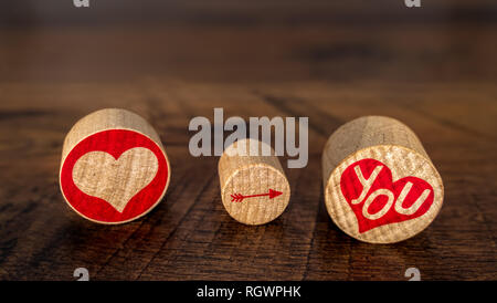T'aime illustré de hart rouge flèche pointant vers le bas sur vous en rouge sur hart pièces liège Saint-valentin idée sur vintage chêne vue avant la décoloration à distance Banque D'Images