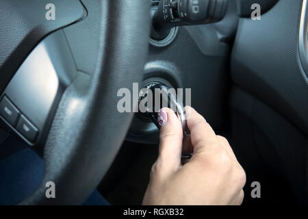 Femme à partir de la voiture. Moment de l'insertion de la clé dans l'allumage du véhicule. L'automobile commence à bouger. Image main de femme libre de tourner la clé de Banque D'Images