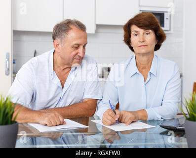 Portrait of mature couple positif au remplissage des documents table de cuisine Banque D'Images