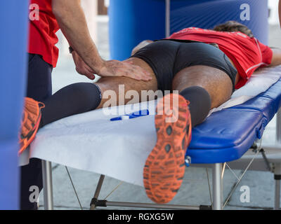 Étendu sur un lit de l'athlète tout en ayant les jambes massées après un entraînement physiques sportives. Banque D'Images