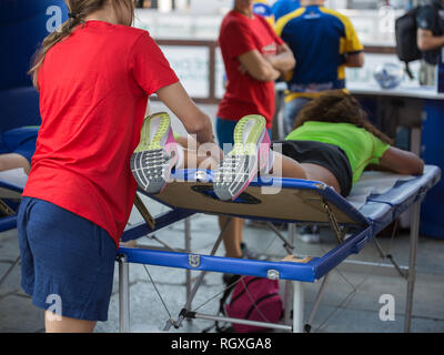 Étendu sur un lit de l'athlète tout en ayant les jambes massées après un entraînement physiques sportives. Banque D'Images