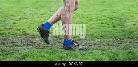 La photo en gros plan d'un jambes du garçon et sneakers couvert de boue après une rencontre de cross-country. Banque D'Images