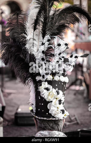 Vue arrière d'un homme portant chapeau haut de forme ou un cylindre décoré avec des plumes durinf un festival masqué Banque D'Images