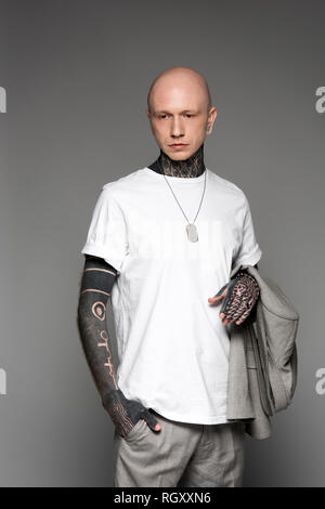 Bald grave tattooed man in white t-shirt tenue veste de costume gris isolé sur Banque D'Images