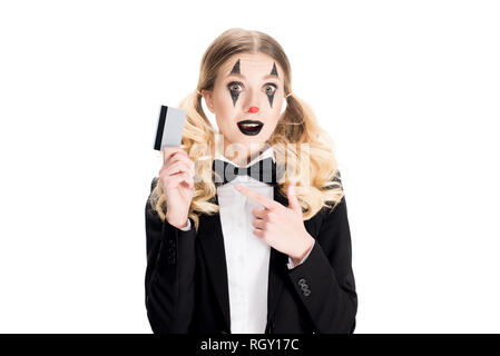 Cheerful female clown pointant du doigt avec carte de crédit isolated on white Banque D'Images