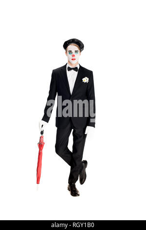 Clown grave en costume et béret noir holding umbrella debout isolated on white Banque D'Images