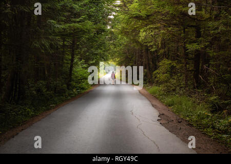 Femme marche sur la pittoresque route forestière pendant une journée d'été. Prises à Florencia Bay, près de l'Ucluelet et Tofino, Vancouver Island, BC, Canada. Banque D'Images