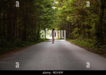 Femme marche sur la pittoresque route forestière pendant une journée d'été. Prises à Florencia Bay, près de l'Ucluelet et Tofino, Vancouver Island, BC, Canada. Banque D'Images