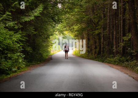 Femme marche sur la pittoresque route forestière pendant une journée d'été. Prises à Florencia Bay, près de l'Ucluelet et Tofino, Vancouver Island, BC, Canada. Banque D'Images