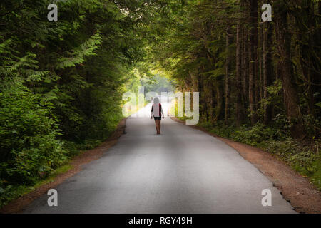 Femme marche sur la pittoresque route forestière pendant une journée d'été. Prises à Florencia Bay, près de l'Ucluelet et Tofino, Vancouver Island, BC, Canada. Banque D'Images