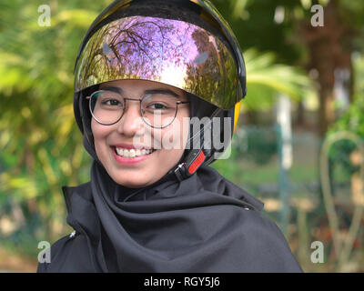 Jolie fille Malais musulmans avec lunettes porte un casque de moto moderne sur son hijab traditionnel. Banque D'Images