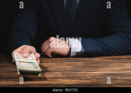 Cropped shot of woman in suit holding roubles russes les billets en main au-dessus de table en bois Banque D'Images