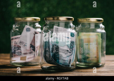 Vue rapprochée d'un bocal en verre avec des billets en roubles russes sur table en bois Banque D'Images