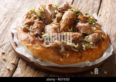 Le plat de poulet aux Palestiniens le sumac, noix de pin et les oignons sur un pain plat libre sur la table horizontale. Banque D'Images