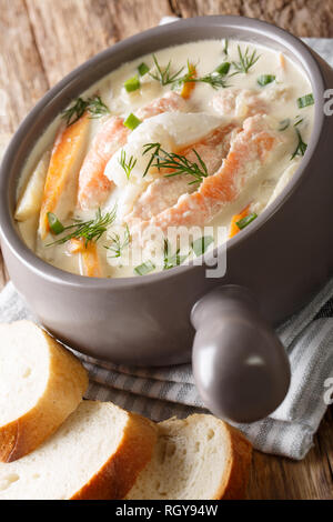 Gros plan du Norwegian fiskesuppe de soupe de poisson crémeux avec la morue et le saumon dans un plat servi avec du pain frais. vertical Banque D'Images