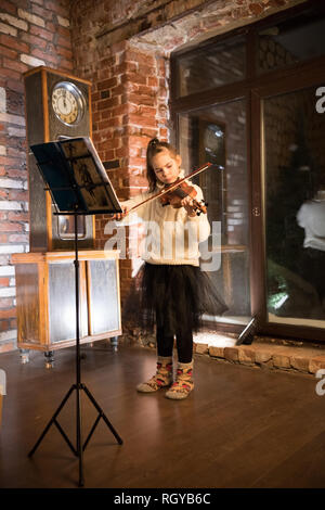 Une petite fille à jouer du violon par des notes Banque D'Images