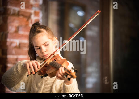 Un peu de belle jeune fille aux cheveux longs à jouer du violon Banque D'Images