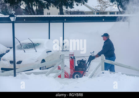 Météo extrêmes de l'hiver ! Un homme le déblayage de la neige sur un trottoir avec une souffleuse à neige mécanique après une tempête hivernale au Michigan, USA. Banque D'Images