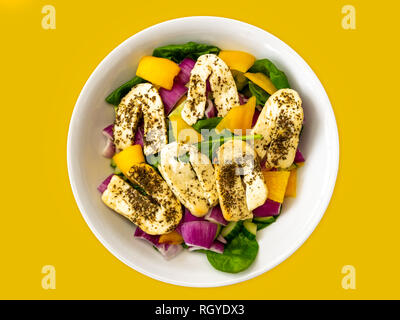 Salade Halloumi dans un bol blanc isolé sur fond jaune Banque D'Images