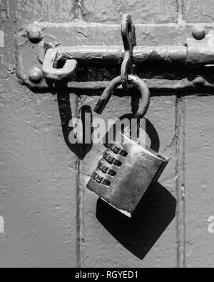 Un vieux cadenas déverrouillé sur une vis en noir et blanc Banque D'Images