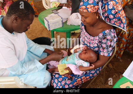 Mopti, Mali. Mar 22, 2018. Une jeune mère tient son bébé qui pleure sur ses genoux tandis qu'un centre de santé employé donne à l'enfant une vaccination. La mère tient sa carte de vaccination du bébé dans la main gauche. Credit : Jürgen Bätz/dpa/Alamy Live News Banque D'Images