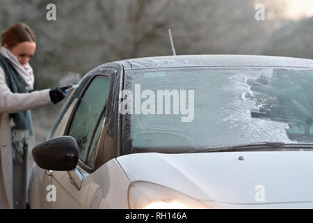 Une femme les éraflures une fenêtre pour éliminer le givre de sa voiture après le Royaume-Uni avait sa nuit la plus froide de l'hiver jusqu'à présent que la vague de froid continue de causer des conditions glacées à travers le pays. Banque D'Images