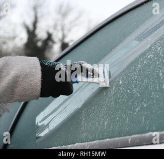 Une femme les éraflures une fenêtre pour éliminer le givre de sa voiture à Peterborough après le Royaume-Uni avait sa nuit la plus froide de l'hiver jusqu'à présent que la vague de froid continue de causer des conditions glacées à travers le pays. Banque D'Images