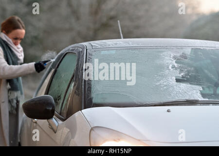 Une femme les éraflures une fenêtre pour éliminer le givre de sa voiture à Peterborough après le Royaume-Uni avait sa nuit la plus froide de l'hiver jusqu'à présent que la vague de froid continue de causer des conditions glacées à travers le pays. Banque D'Images