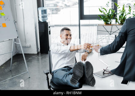 Smiling businessman de trinquer avec un verre d'alcool dans le verre avec un collègue de bureau moderne Banque D'Images