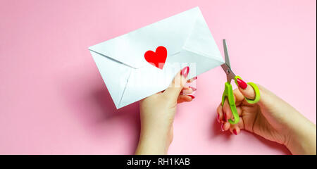 La main féminine s'ouvre l'enveloppe avec un cœur rouge. Une lettre d'amour à l'être aimé. Valentines Day concept. Carte de voeux saint valentin. Déclaration d'amour. Weddi Banque D'Images
