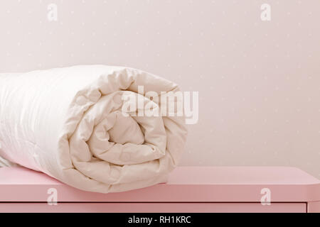 Une couette enroulée est couchée sur la commode. Couverture pour un lit Banque D'Images