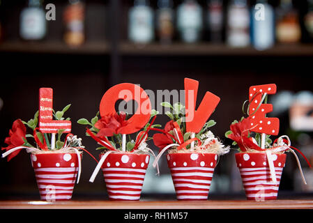 Des lettres d'amour dans les pots de fleurs sur fond flou de la barre. Banque D'Images