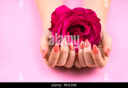 Woman's hands holding manucure Corail avec rose. Banque D'Images