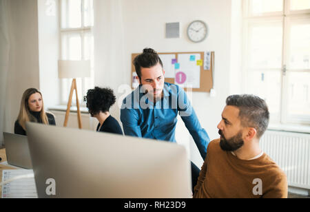 Groupe de jeunes hommes et femmes d'affaires concentré avec portable travaillant dans un bureau moderne. Banque D'Images