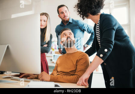 Groupe de jeunes hommes et femmes concentré d'affaires avec ordinateur portable ayant une réunion dans un bureau moderne. Banque D'Images