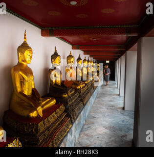 Jeune femme ressemble à la rangée de statues de Bouddha d'Or de Wat Pho Thaïlande Bangkok Palace Banque D'Images