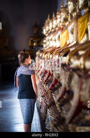 Jeune femme ressemble à la rangée de statues de Bouddha d'Or de Wat Pho Thaïlande Bangkok Palace Banque D'Images