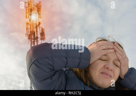 La femme tient sa tête près de la BTS. Rayonnement nocif par le réseau de téléphonie mobile concept transmetteurs Banque D'Images