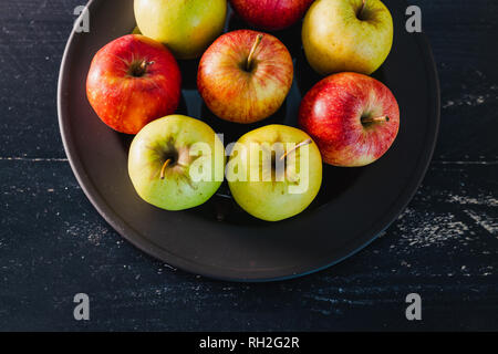 Groupe de mélange organique couleurs rouge, vert et jaune des pommes sur la plaque noire sur fond noir, concept de choisir les meilleurs produits et des aliments sains Banque D'Images