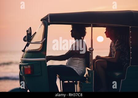 Conducteur et passager sont voyageant en tuk tuk taxi contre la mer au coucher du soleil au Sri Lanka. Banque D'Images