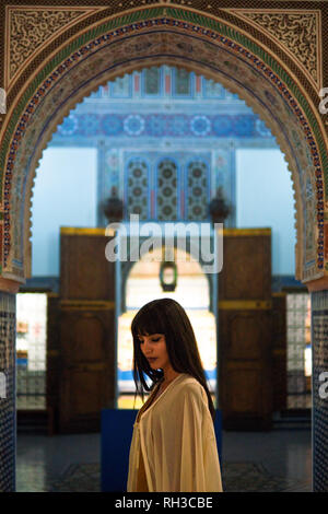 Belle Jeune Fille marocaine en robe d'or court et blanc manteau manteau en intérieur riche de la pittoresque ville de Riyad Dar Si Said à Marrakech. Banque D'Images