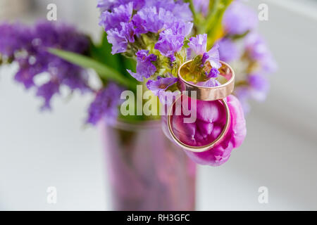 Concept de mariage : bouquet de tulipes multicolores et deux anneaux de tissu en satin blanc Banque D'Images